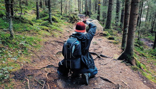 Rear view of a man holding dirt road in forest