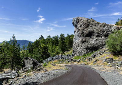 Road amidst rocks and trees against sky