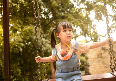 Cute girl sitting on swing at park