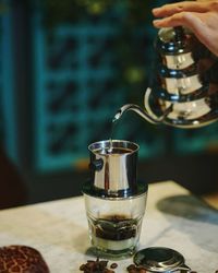 Close-up of hand pouring drink in glass on table