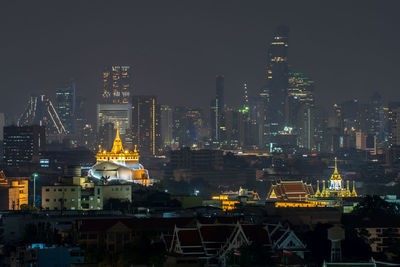 Illuminated buildings in city against sky at night