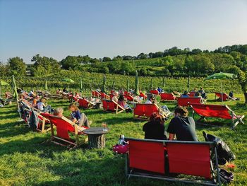 People sitting on chair in field against clear sky