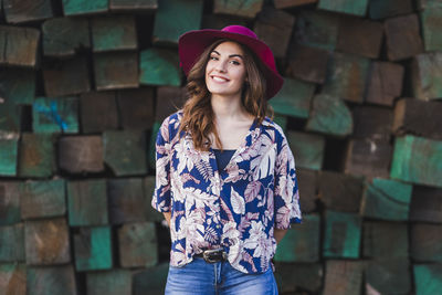 Portrait of smiling young woman standing against wall