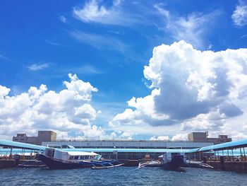 Boats in sea against cloudy sky