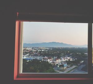 Buildings in city against sky seen through window