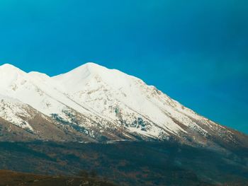 Scenic view of snowcapped mountains against clear blue sky