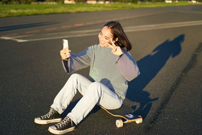 Side view of woman sitting on road