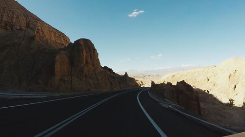 Road leading towards mountains against sky