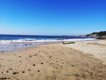 Scenic view of beach against clear blue sky