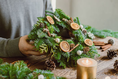 The hands of a male florist makes a new year's drenching from fresh spruce branches, cones an