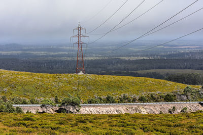 Electricity pylon on field against sky