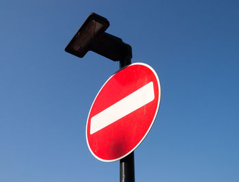 Low angle view of road sign against clear blue sky