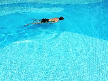 High angle view of shirtless man swimming in pool