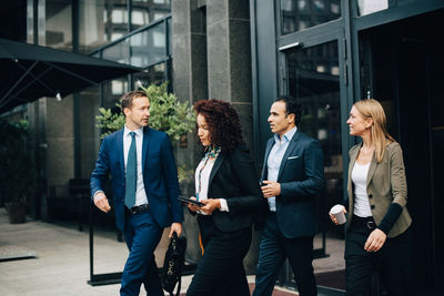 Multi-ethnic business colleagues walking against building in city