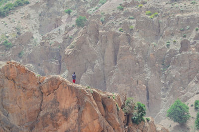 Rear view of man walking on rocks against mountains