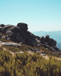 Scenic view of rocks by sea against clear sky