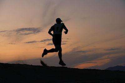 Full length of silhouette man jumping against sky during sunset