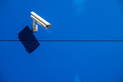 Close-up of security camera mounted on blue wall