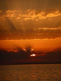 Scenic view of sea against dramatic sky during sunset