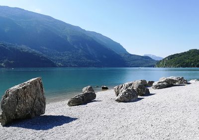 Scenic view of sea and mountains against clear blue sky