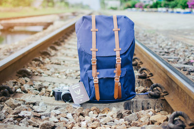 Close-up of backpack and camera with passport on railroad track