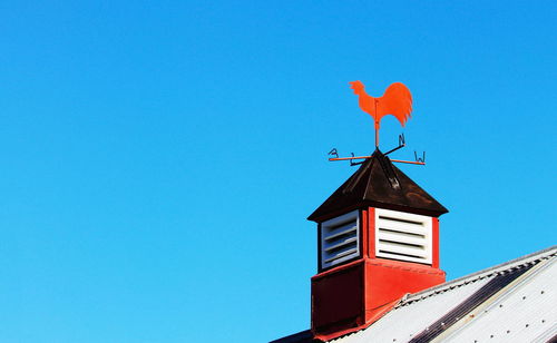 Low angle view of red house against clear blue sky