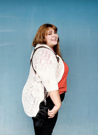 Portrait of young woman standing against blue wall