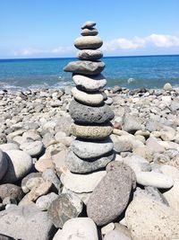 Stack of stones on beach against sky