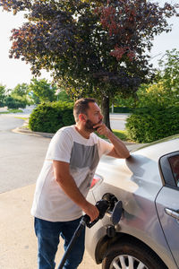 Side view of young man riding motor scooter on road