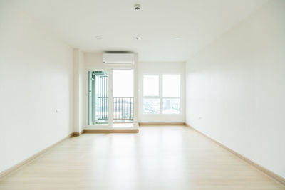 Empty room is decorated with an engineering wooden floor and wallpaper on the wall.