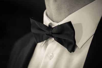 Midsection of businessman wearing bow tie against black background