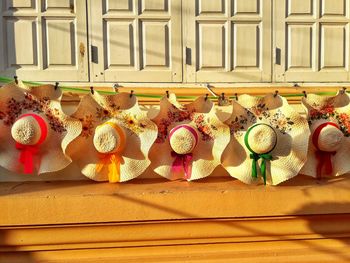 White hand-woven hats hanging under white wooden window