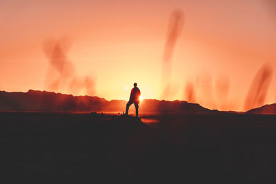 Silhouette man standing on mountain during sunset