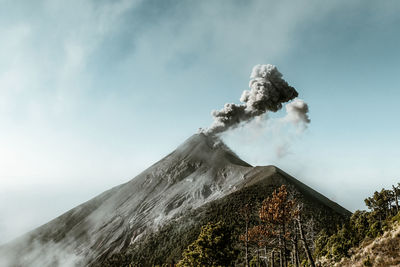 Low angle view of smoke emitting from volcanic mountain against sky