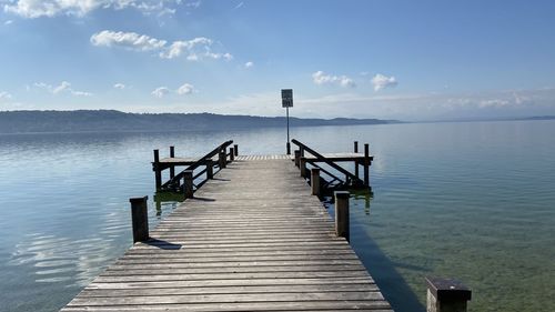 Wooden jetty on pier over lake against sky