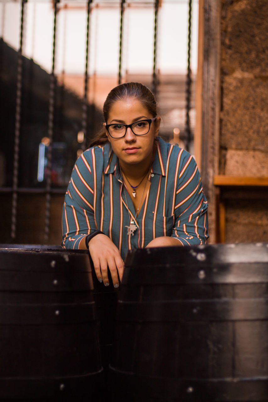 portrait, front view, one person, real people, looking at camera, indoors, young adult, waist up, music, young women, lifestyles, adult, women, sitting, casual clothing, eyeglasses, glasses, hairstyle, beautiful woman