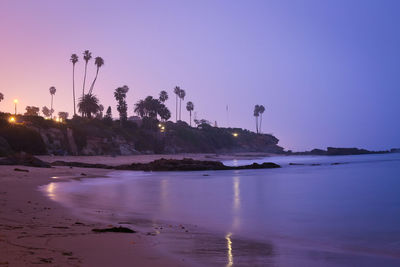 Scenic view of beach against sky at sunset