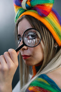 Close-up portrait of young female model holding magnifying glass