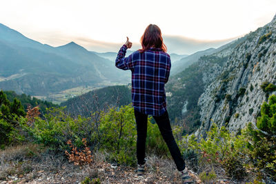 Rear view of woman standing on mountain against sky
