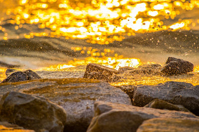 Close-up of rocks in sea during sunset