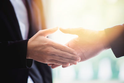 Midsection of businessman and colleague shaking hands at office