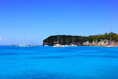 Sailboats in sea against clear blue sky