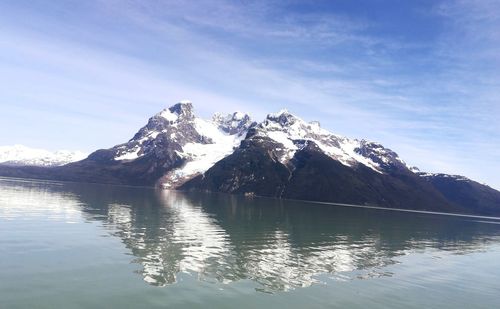 Scenic view of lake by snowcapped mountains against sky