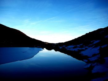 Scenic view of lake and mountains against blue sky