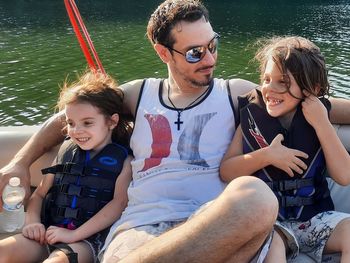 Happy friends sitting on boat in water