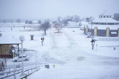 Snow covered landscape with buildings in background