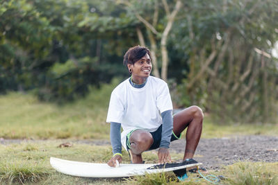 Man looking away while polishing surfboard