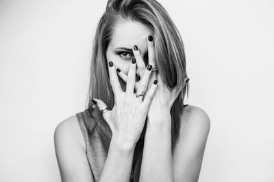 Portrait of woman with hands on face against white background