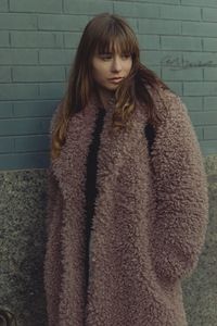 Woman standing against wall in winter