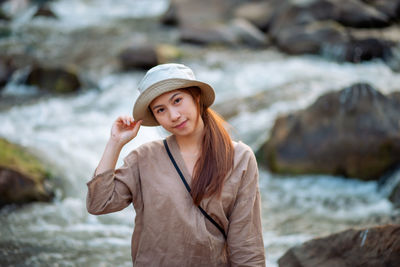 Portrait of beautiful young woman standing on rock